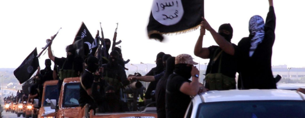 Das Bild zeigt Kämpfer auf den Ladeflächen ihrer Pick-ups mit der Fahne der Terrororganisation Islamischer Staat (IS).