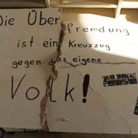 Das Bild zeigt ein Plakat mit der Aufschrift: "Die Überfremdung ist ein Kreuzzug gegen das eigene Volk!"
