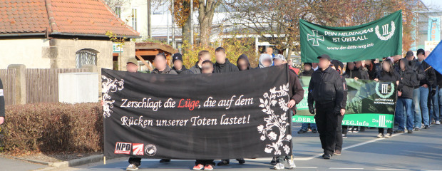 Das Bild zeigt Demonstrationsteilnehmer der Parteien NPD und Der Dritte Weg, die Banner mit den Schriftzügen "Zerschlagt die Lüge, die auf dem Rücken unserer Toten lastet" sowie "Dein Heldengrab ist überall" tragen. Das Bild zeigt Demonstrationsteilnehmer der Parteien NPD und Der Dritte Weg, die Banner mit den Schriftzügen "Zerschlagt die Lüge, die auf dem Rücken unserer Toten lastet" sowie "Dein Heldengrab ist überall" tragen.