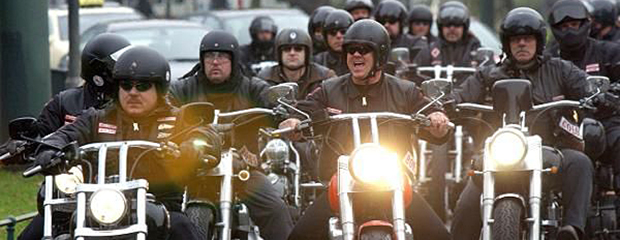 Das Bild zeigt mehrere schwarzgekleidete Mitglieder einer Rockergruppierung auf ihren Motorrädern bei einer Ausfahrt. 