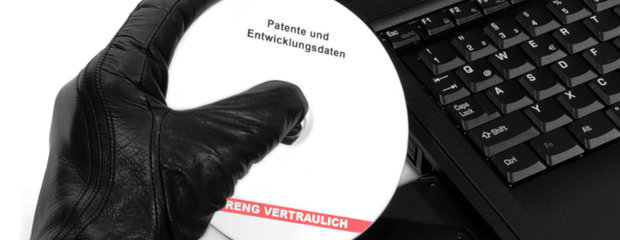 Das Bild zeigt eine Hand im schwarzen Handschuh, die eine weiße CD mit der Aufschrift "Patente und Entwicklungsdaten - Streng vertraulich" aus dem CD-Laufwerk eines Laptops entwendet.